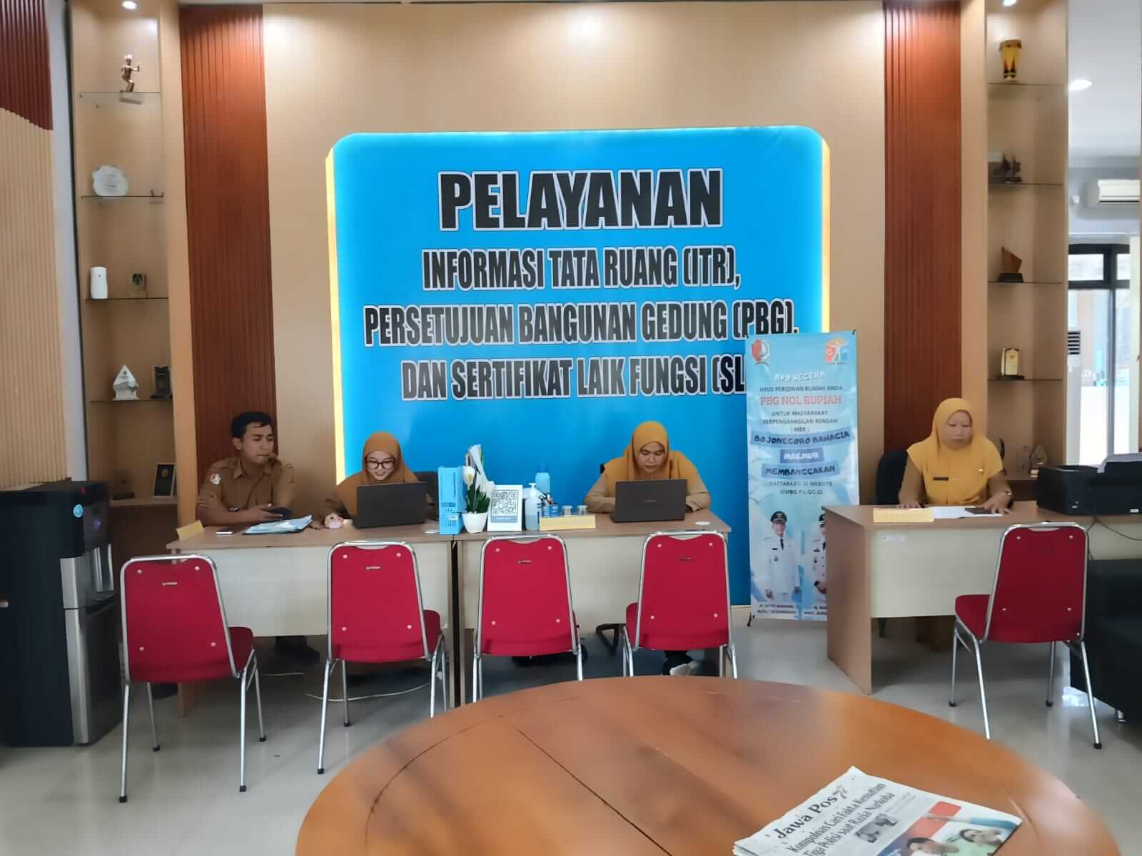 Ruang khusus pelayanan Persetujuan Bangunan Gedung (PBG) di DPMPTSP Kabupaten Bojonegoro yang disediakan sebagai pusat konsultasi bagi masyarakat. Empat petugas dari lintas organisasi perangkat daerah (OPD) disiagakan untuk memberikan pendampingan dan penjelasan terkait proses pengajuan PBG, kelengkapan administrasi, hingga persyaratan teknis sesuai ketentuan yang berlaku. Foto : Newsbojonegoro.com