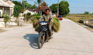 Petani melintasi jalan cor beton hasil pembangunan Program BKKD di Desa Banjarejo Kecamatan Sumberrejo Bojonegoro.