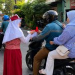 Siswa SDN Campurejo 1 Bojonegoro membagikan bendera Merah Putih kepada pengendara