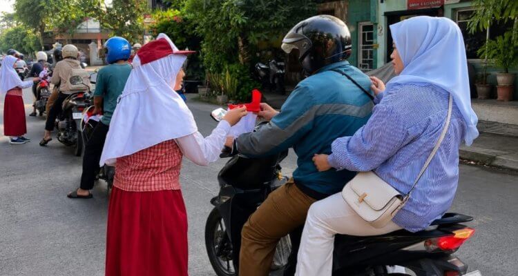 Siswa SDN Campurejo 1 Bojonegoro membagikan bendera Merah Putih kepada pengendara