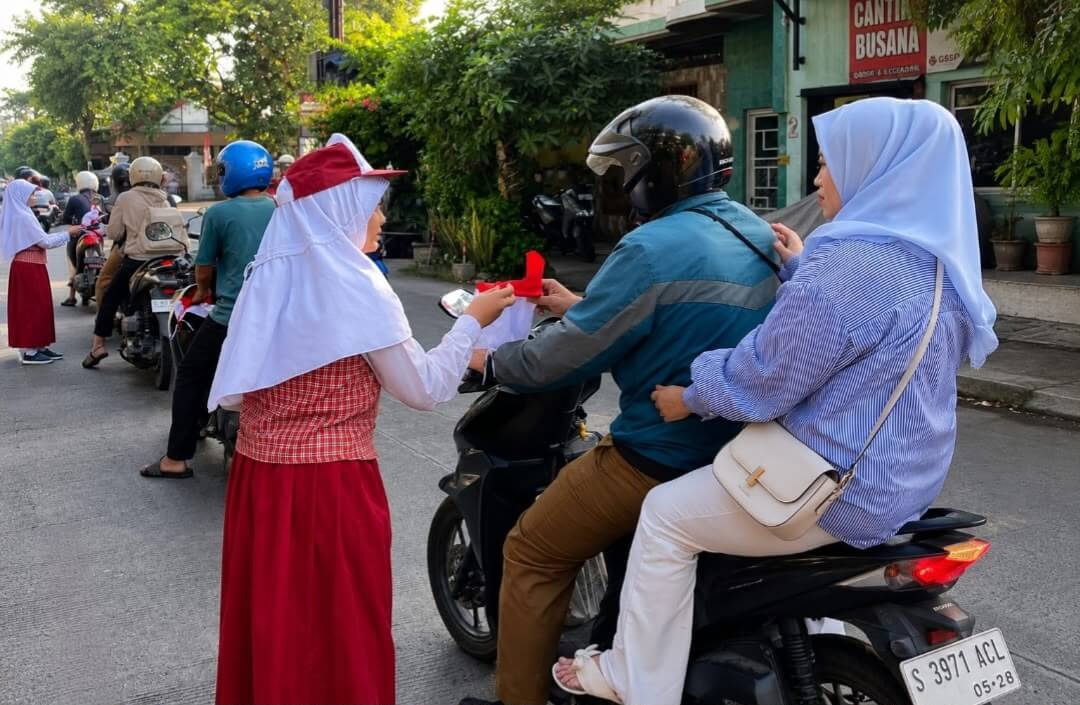 Siswa SDN Campurejo 1 Bojonegoro membagikan bendera Merah Putih kepada pengendara