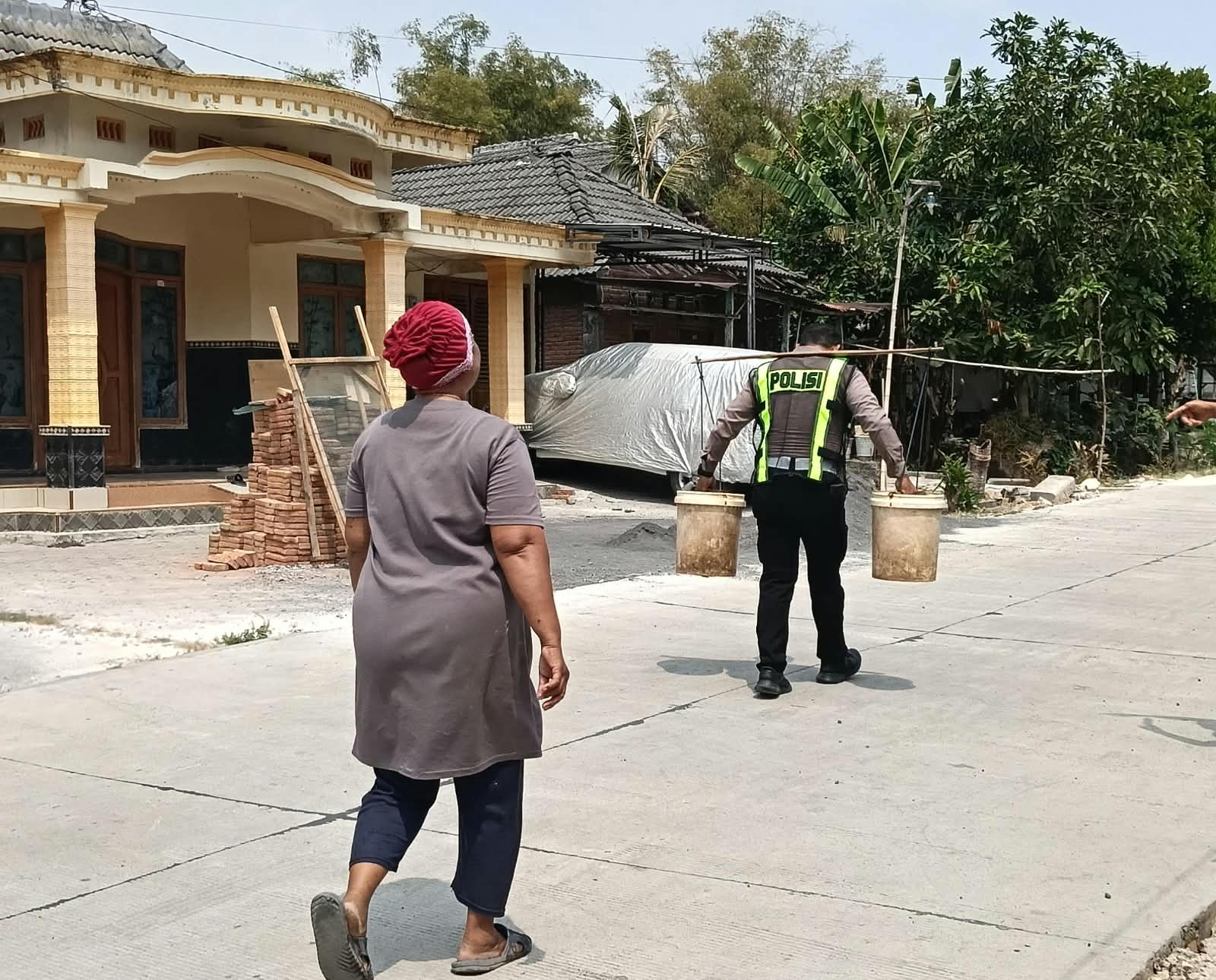Aiptu Edi S. turut membantu mengantarkan air bersih hingga ke rumah warga yang lokasinya cukup jauh dari titik penampungan, sebagai bagian dari kegiatan bakti sosial Satlantas Polres Bojonegoro.